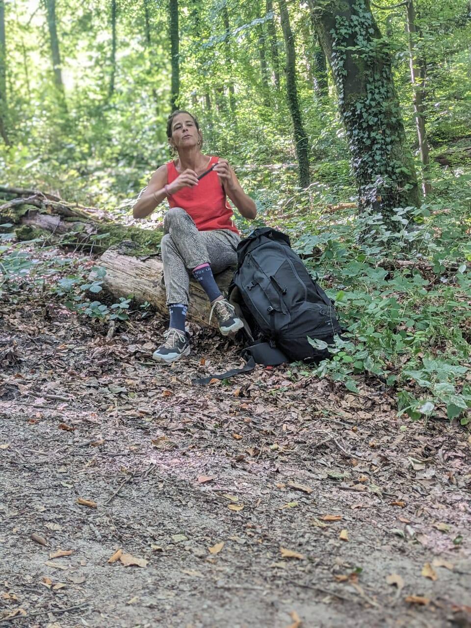 Adulte en pause assis sur un tronc en forêt